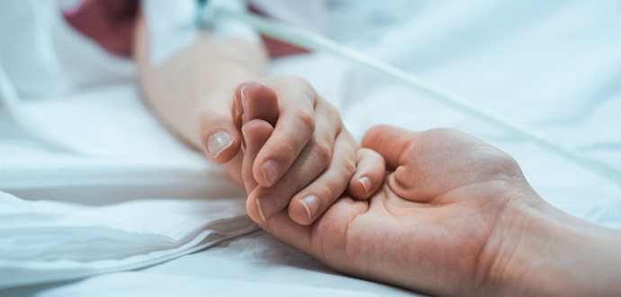 Patient holds family member's hand in hospital bed