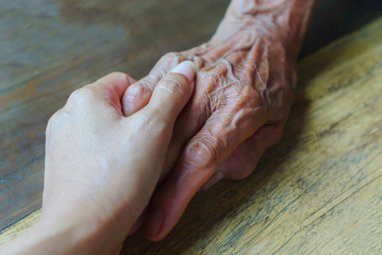 Elderly woman holding someone's hand in a nursing home.