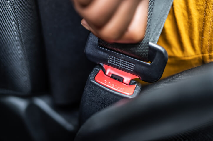 person buckling up seatbelt