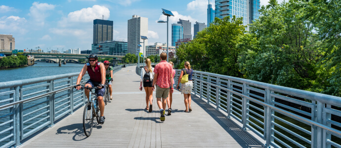 Bicyclists and pedestrians on path in sunny city