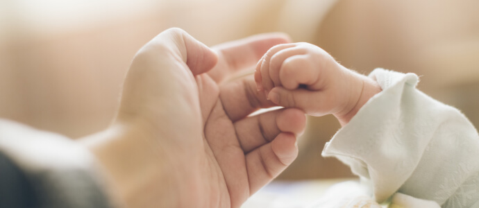 Little baby's hand holding onto parent's finger