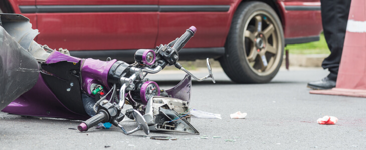 broken motorcycle next to a car