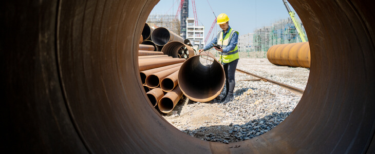 Construction worker laying pipes down on a railroad