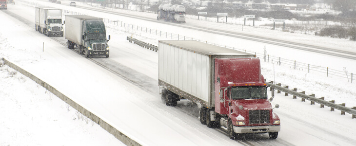 Snow-covered highway with large semi-trucks driving through