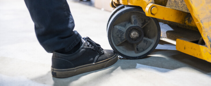 Man's foot next to a pallet jack tire