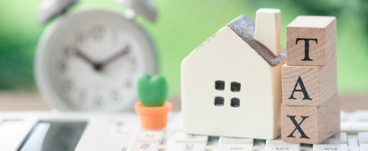 Miniature house next to letter blocks spelling TAX