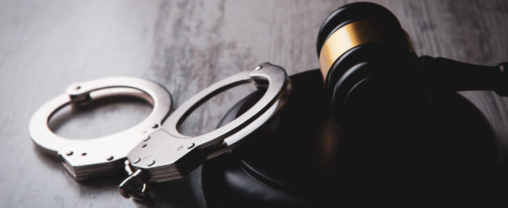 Handcuffs next to a judge's gavel